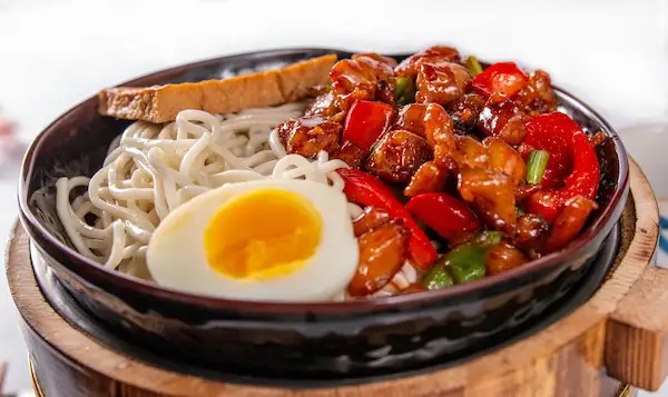 Kung Pao chicken mixed noodles with bell peppers and a soft-boiled egg